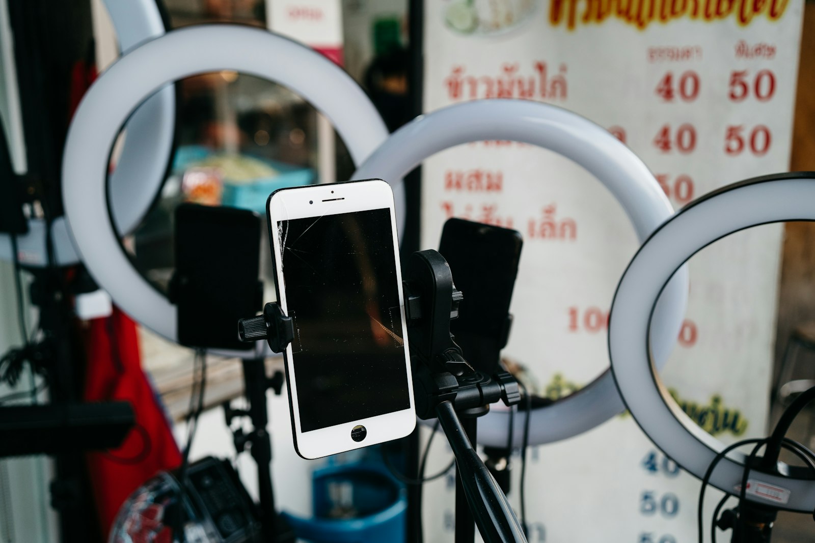 มือถือบนขาตั้งพร้อมไฟวงแหวนหน้าร้านอาหารไทย — อุปกรณ์ครีเอเตอร์สายวิดีโอสั้น