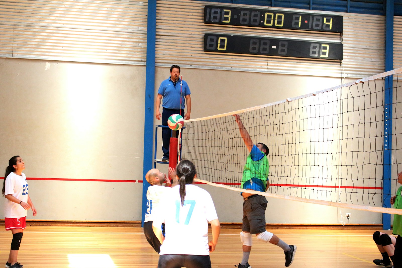Volleyball player spiking over the net in an indoor arena
