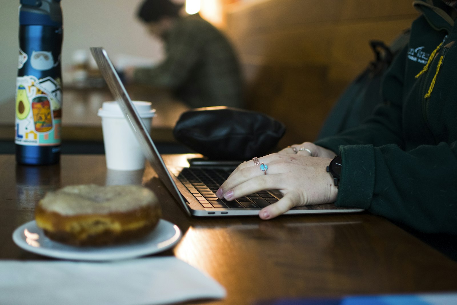 Person working on a laptop and phone in a café
